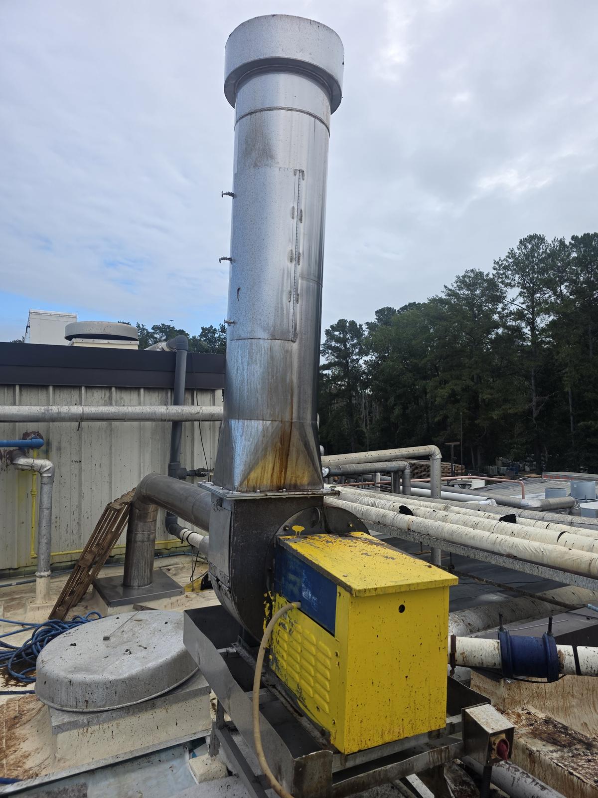 A second belt-driven roof exhaust fan. Orange and yellow corrosion staining runs down the transition beneath the stack.